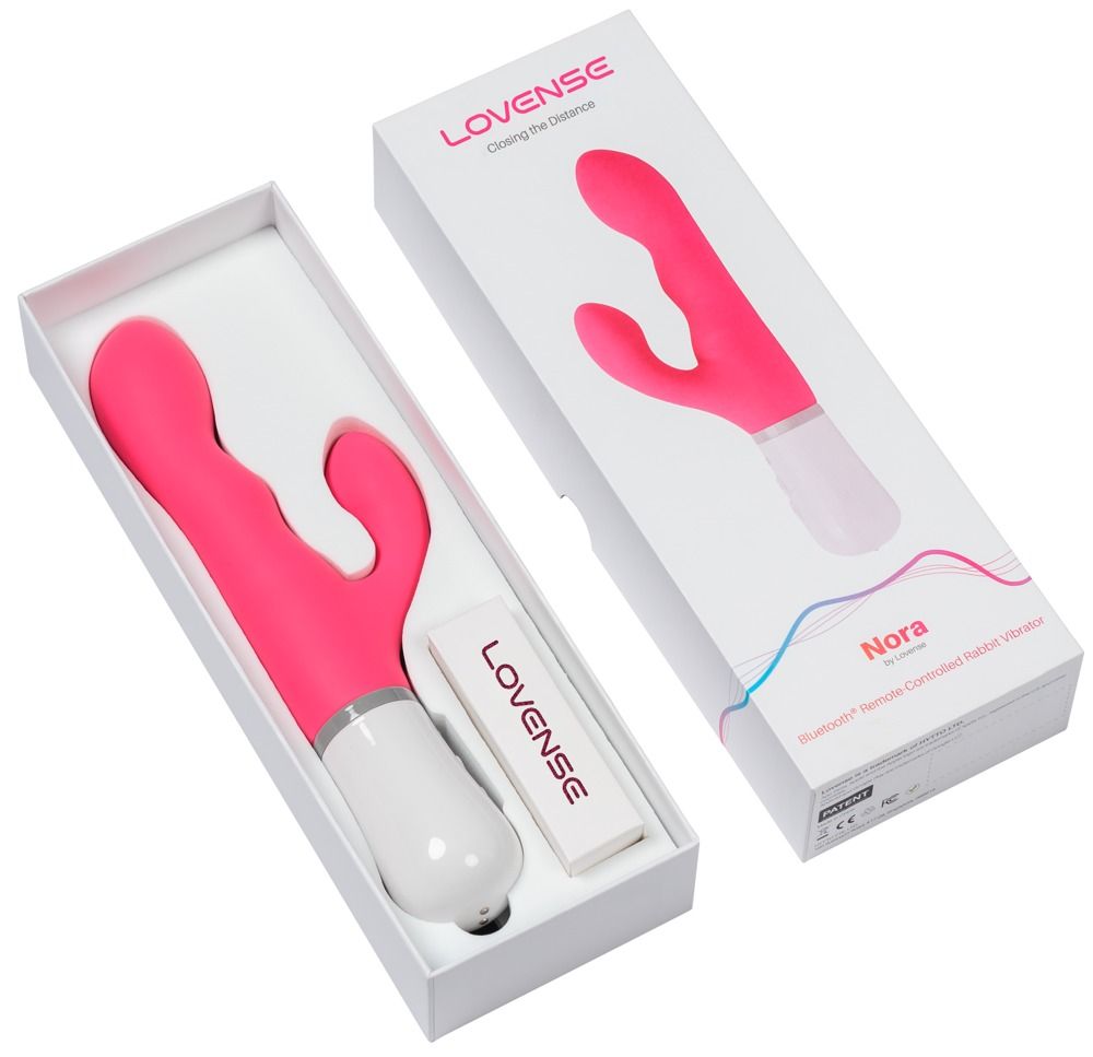 Geöffnete Verpackung mit rosa Vibrator, Bedienungsanleitung und Produktname 'Nora'.