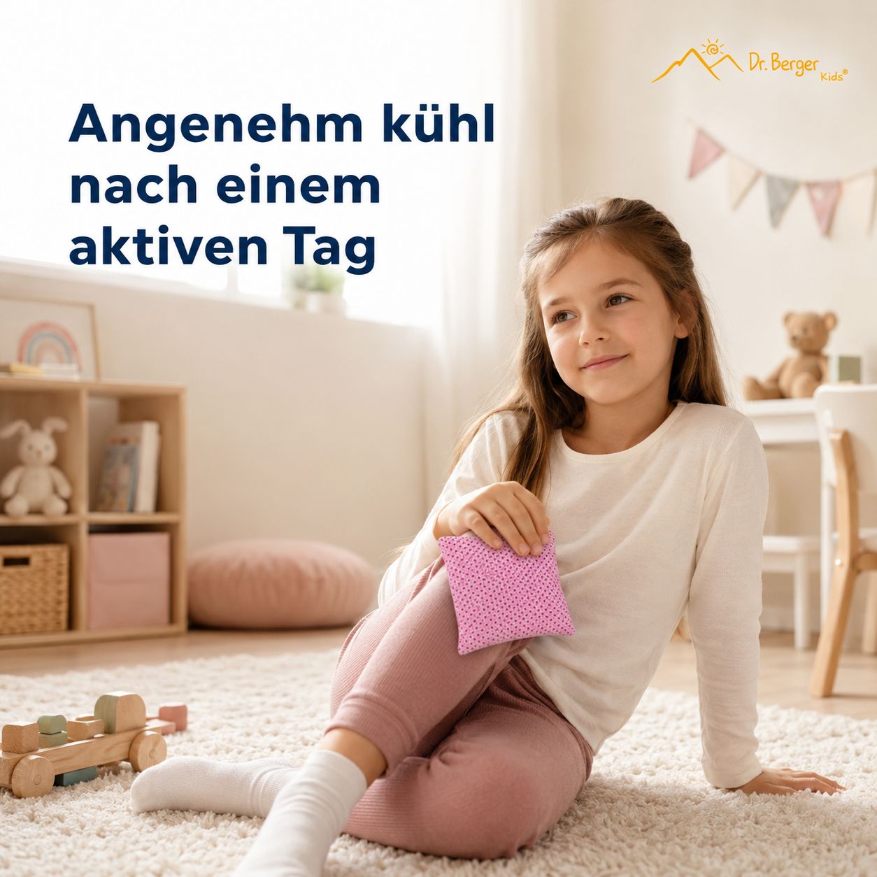 Mädchen sitzt auf Teppich und hält rosa Kirschkernkissen.