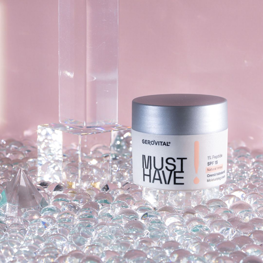Creme-Tiegel auf Glasperlen und Glasblöcken. Aufschrift: MUST HAVE, 1% Peptid, SPF 15, Natural tinted, Creme hidratantă, Moisturizing cream.