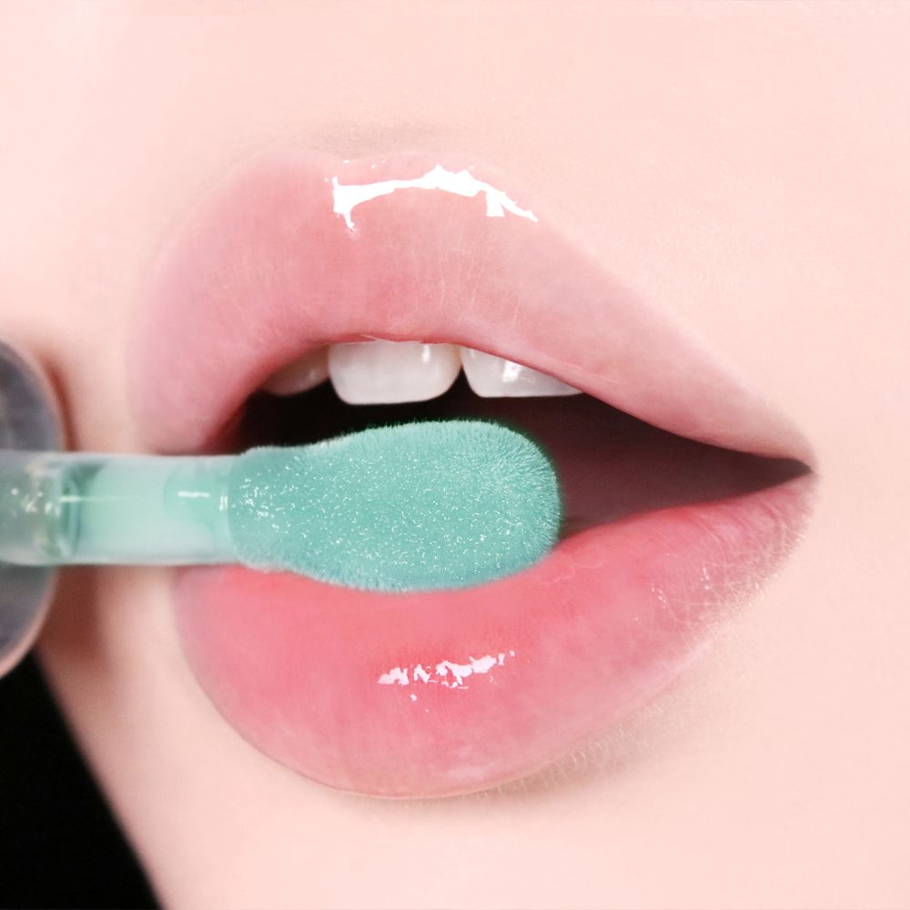 Lippen mit aufgetragenem Lip Oil. Der Applikator ist sichtbar. Die Lippen sind glänzend und rosa.