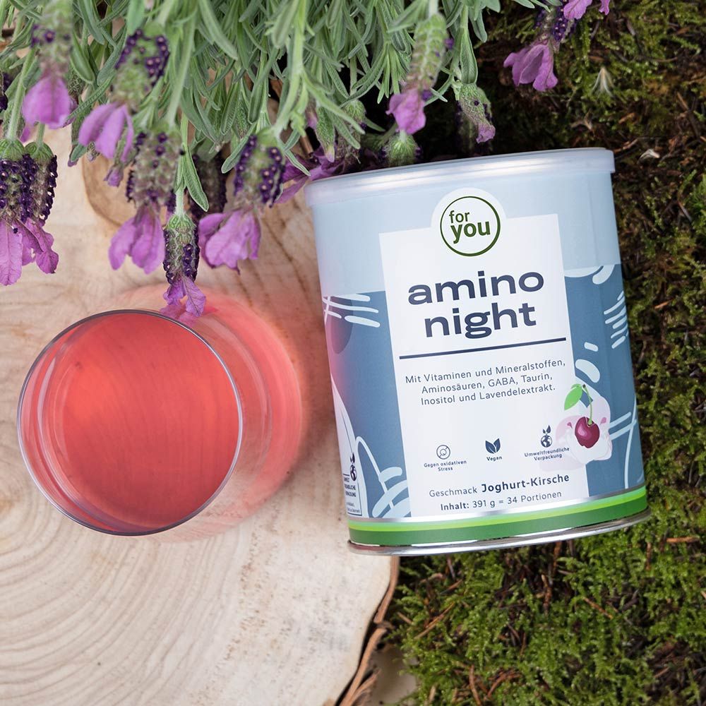 Dose "for you amino night" neben Glas mit roter Flüssigkeit und Lavendelblüten. Produkt auf natürlichem Hintergrund. Dose mit Produktinformationen.