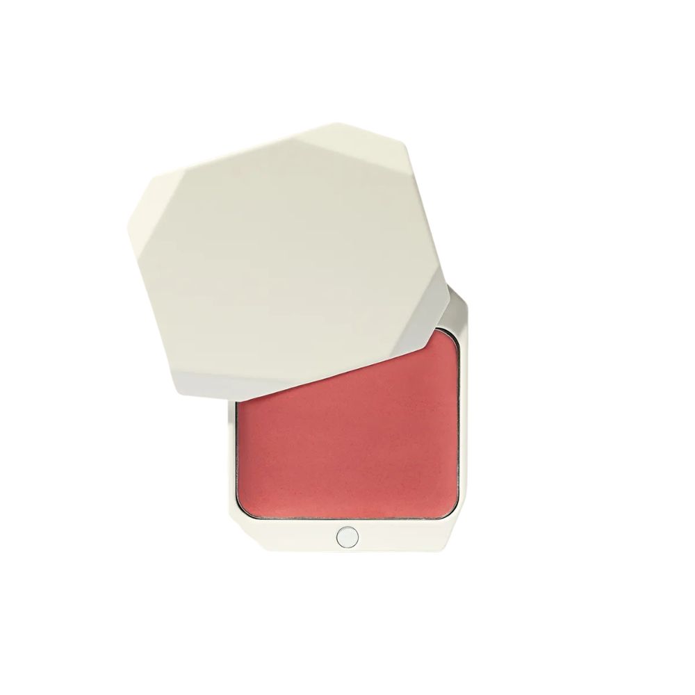 Kosmetikprodukt. Weißer, sechseckiger Behälter mit hochgeklapptem Deckel. Innen rosa getönte Creme. Kleiner, runder Knopf am Boden.