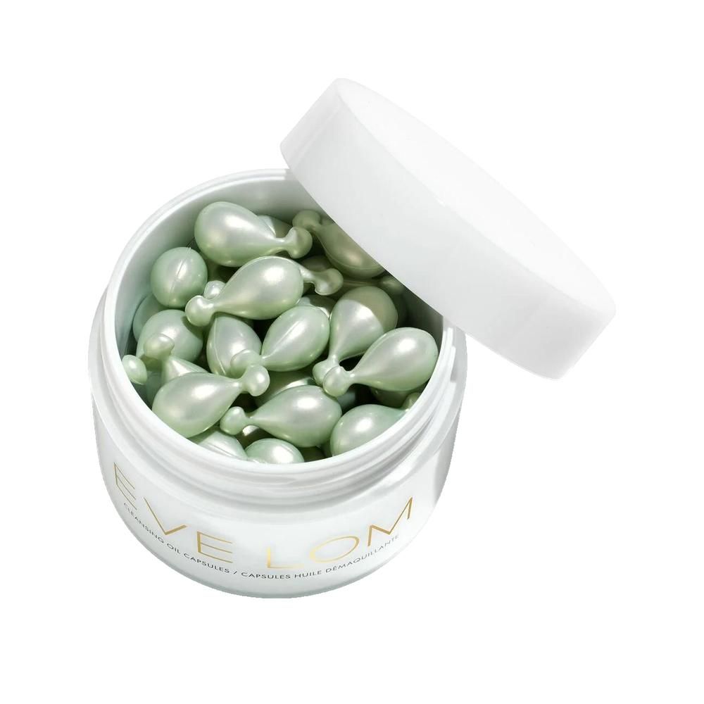 Geöffnete weiße Dose mit grünen, tropfenförmigen Kapseln. Deckel liegt daneben.