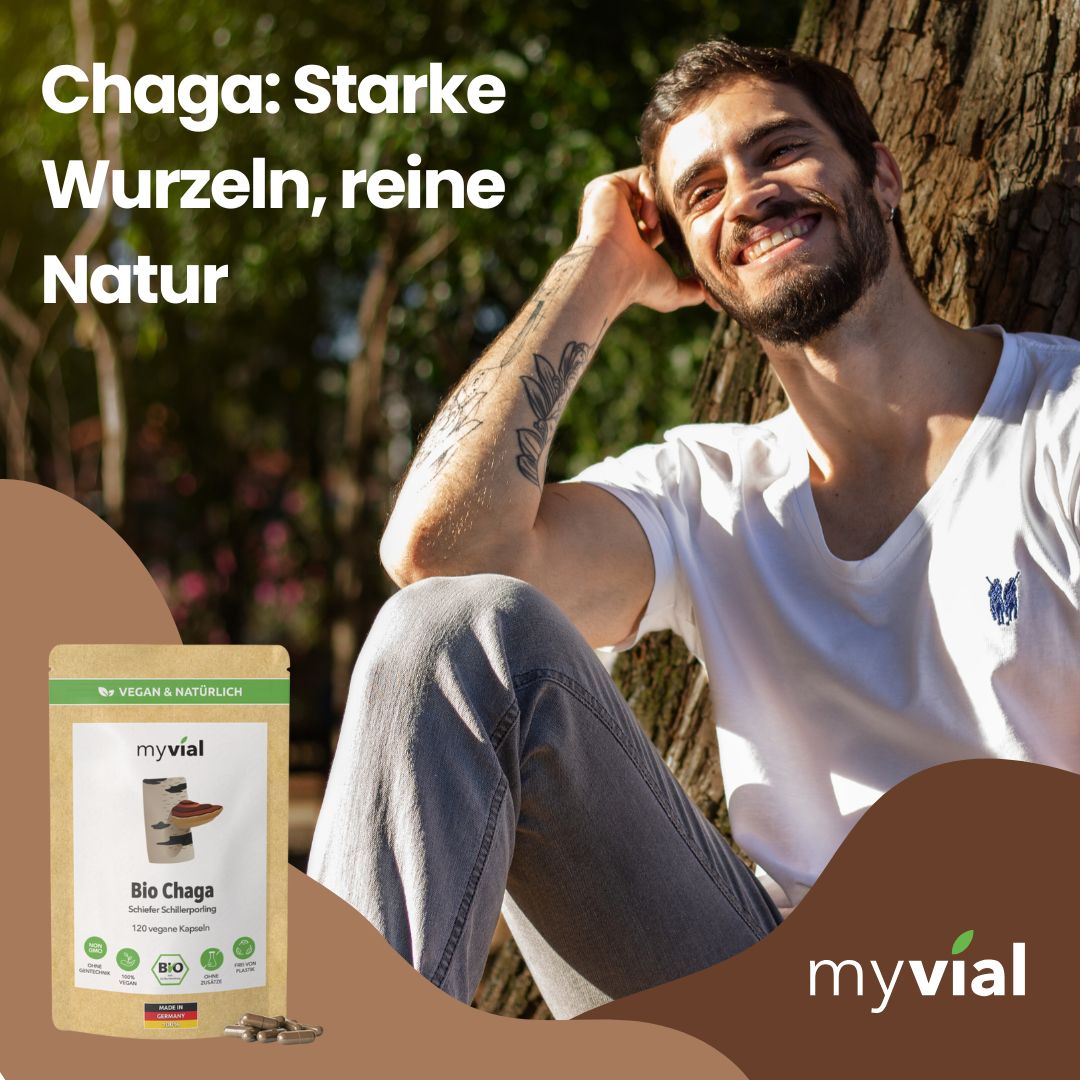 Lächelnder Mann sitzt im Freien neben einem Baum. Ein myvial Bio Chaga Kapsel Beutel ist sichtbar.