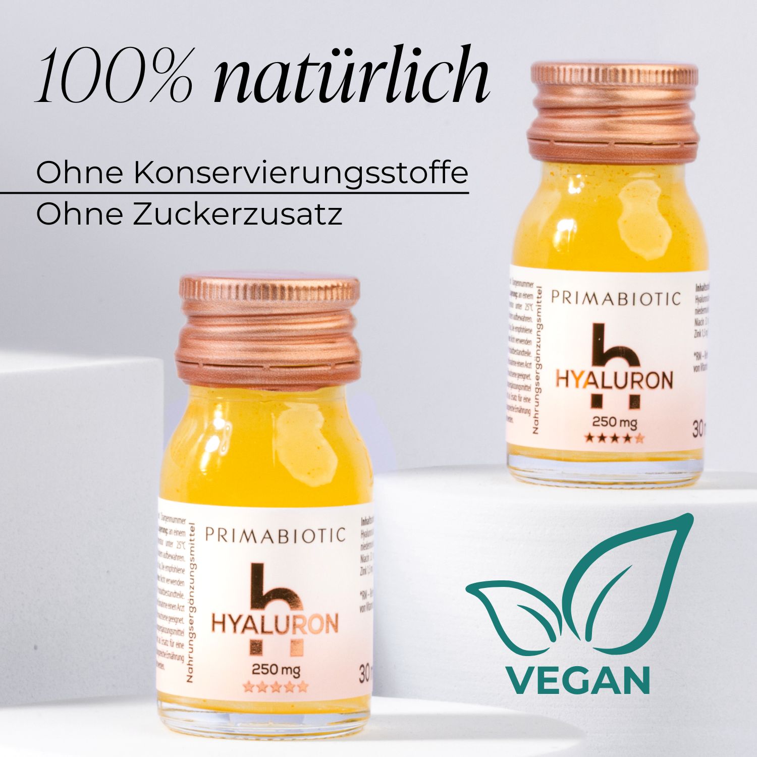 Zwei Flaschen Primabiotic Hyaluron. Text: "100% natürlich", "Ohne Konservierungsstoffe", "Ohne Zuckerzusatz". Vegan-Logo.