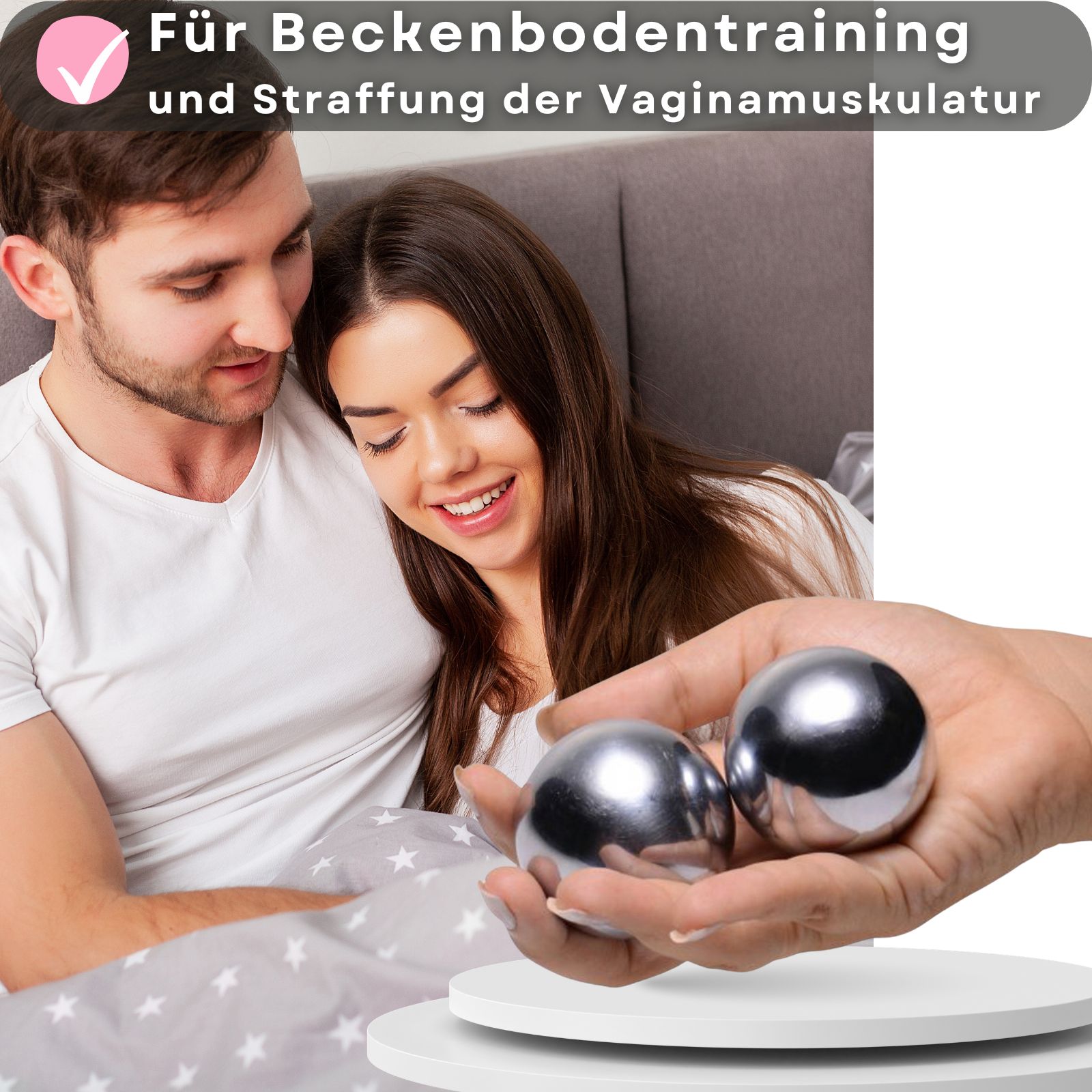 Zwei metallische Kugeln in einer Hand. Paar liegt auf einer weißen Oberfläche. Paar liegt auf einem Bett.