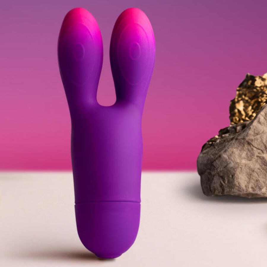 Lila Vibrator mit Hasenohren-Design. Farbverlauf von Lila zu Pink. Auf weißem Untergrund mit Stein und Gold.