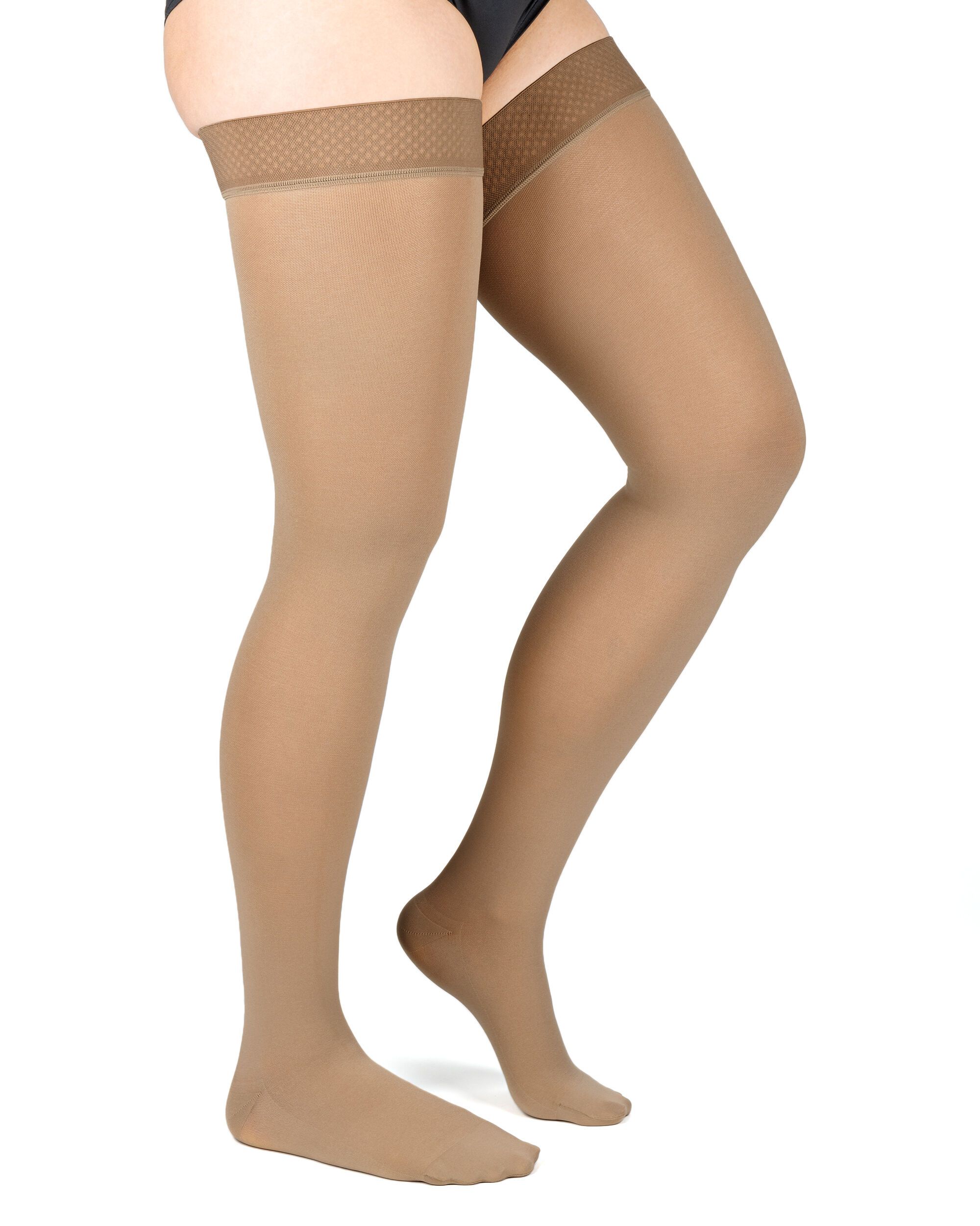 Hautfarbene Kompressions-Schenkelstrümpfe mit Haftband. Blick von der Seite auf die Beine einer Person. Der Strumpf bedeckt den Fuß.