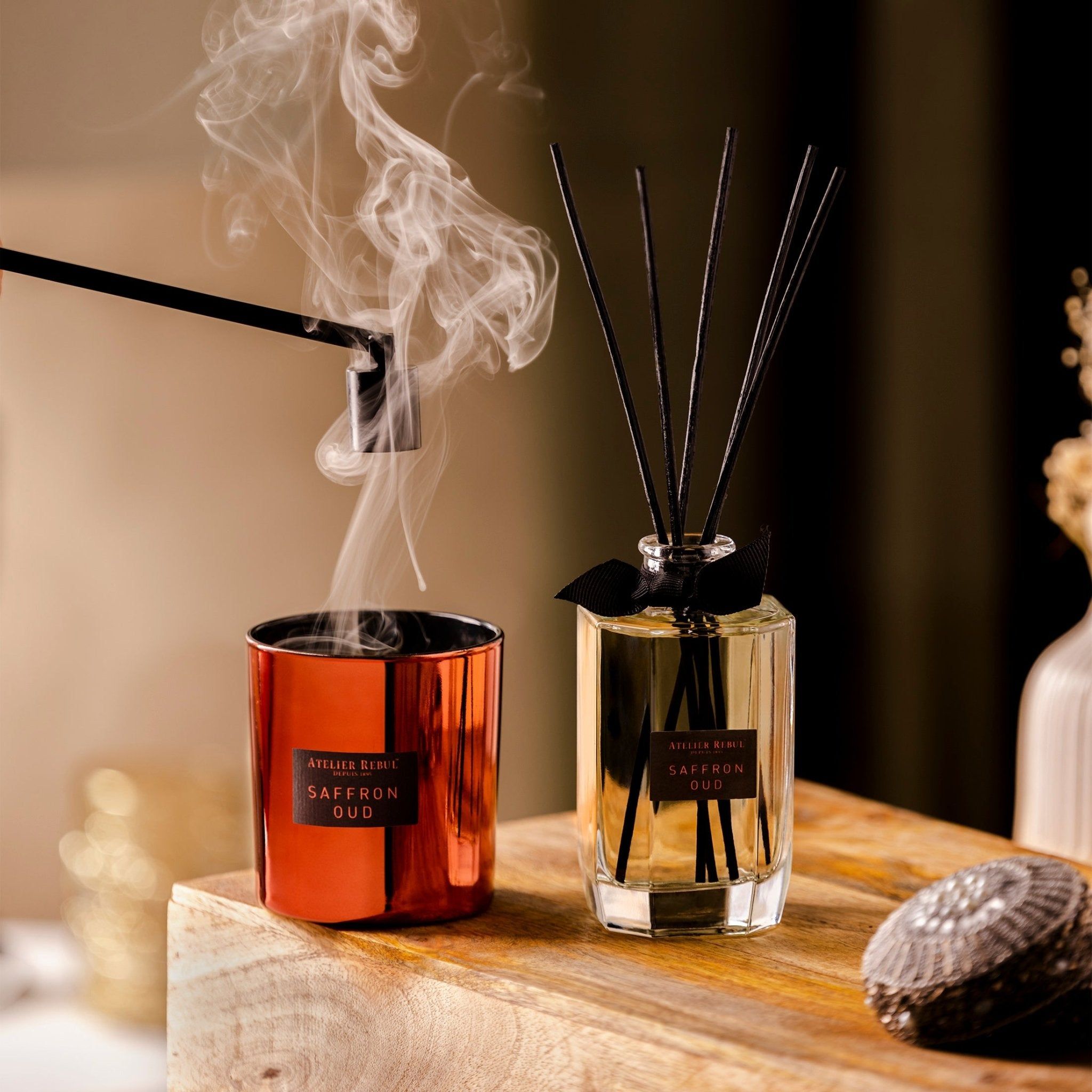 Eine Atelier Rebul Kerze und ein Diffusor mit Duftstäbchen, beide mit dem Duft Saffron Oud.