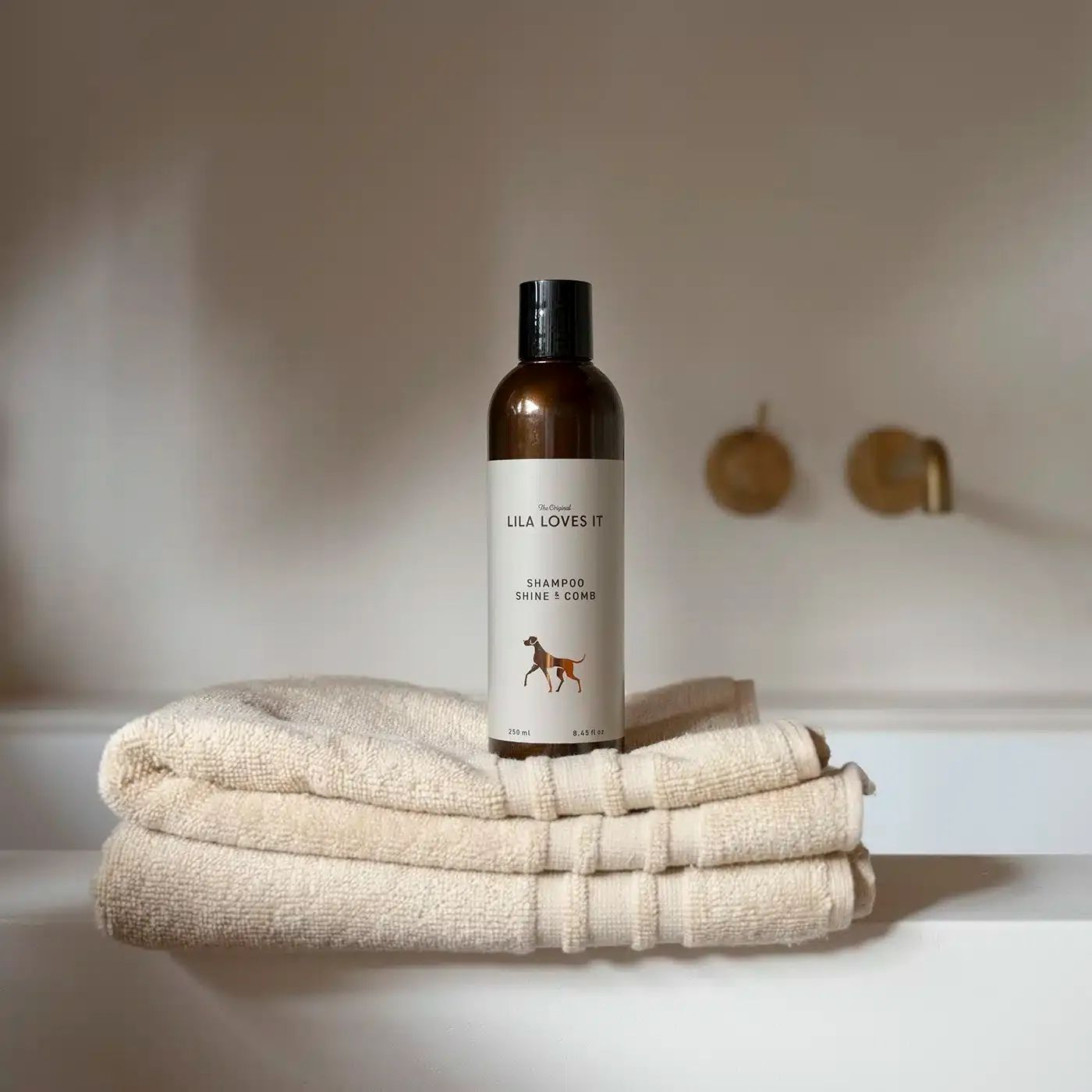 Braune Shampoo-Flasche mit schwarzem Deckel auf gefalteten Handtüchern. Logo und Produktname sichtbar.