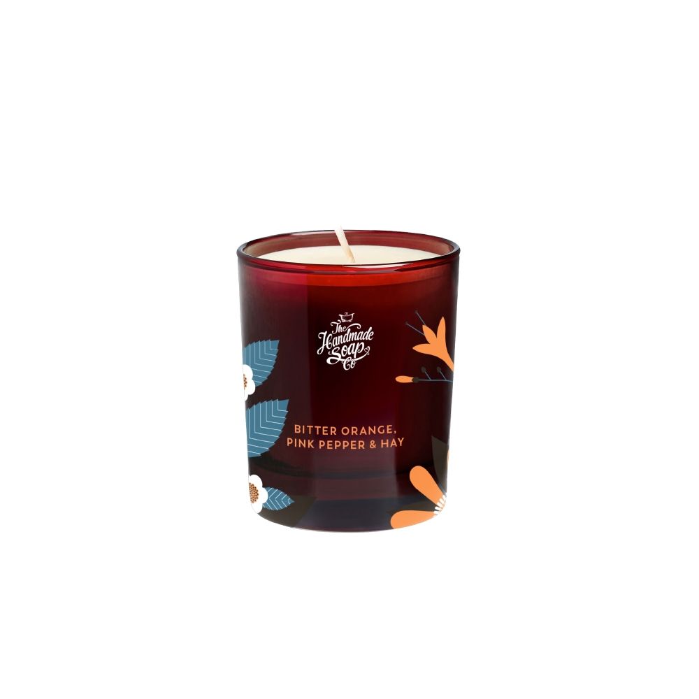 Kerze in einem roten Glas. Aufschrift: Bitter Orange, Pink Pepper & Hay. Marke: The Handmade Soap Co.