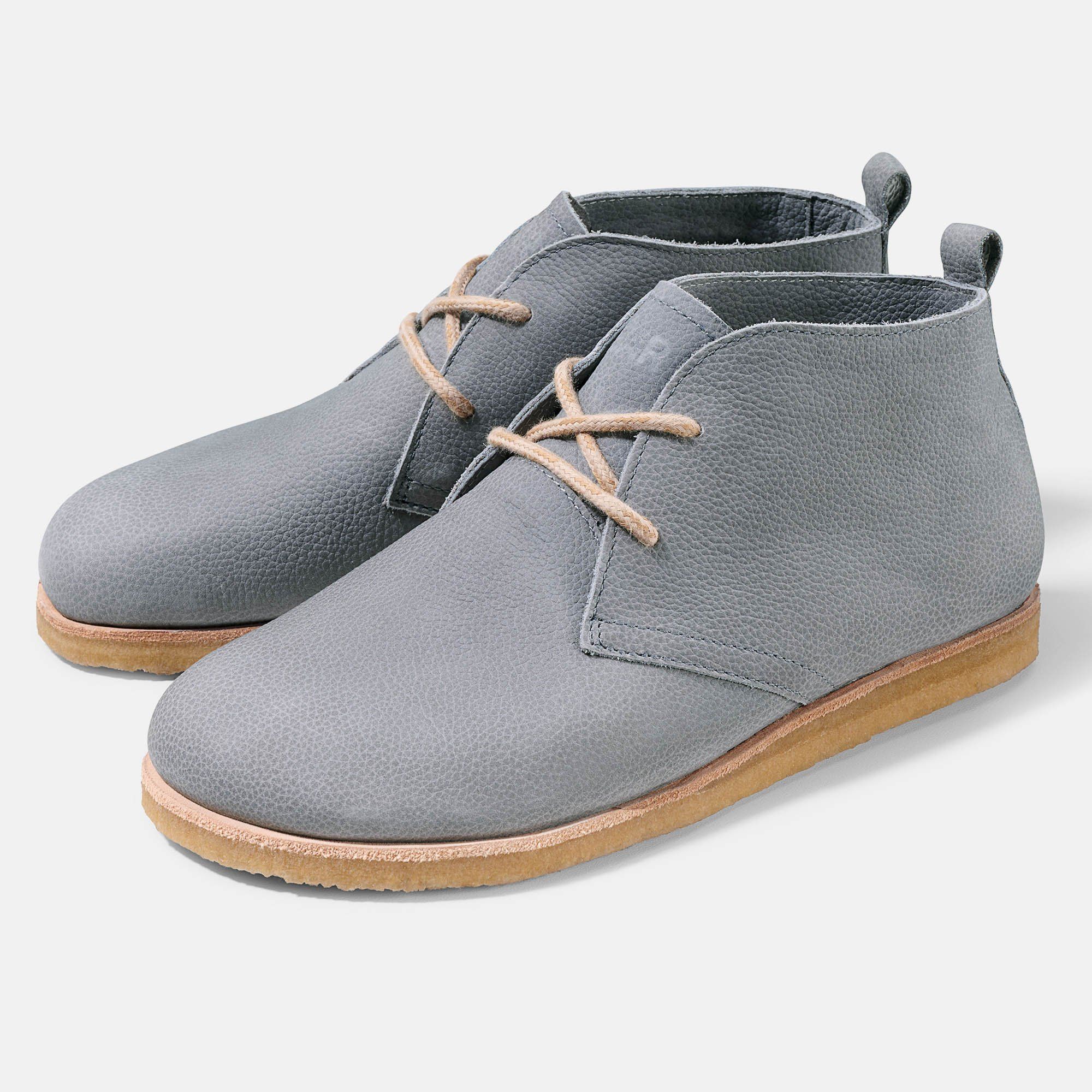 Graue Stiefeletten mit Schnürsenkeln und heller Sohle. Zwei Schuhe nebeneinander, leicht schräg gestellt.