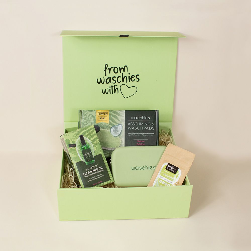Grüne Box mit Produkten. Enthält Waschpads, Reinigungsöl, Abschminkpads, eine Tasche und ein Päckchen. Aufschrift: from waschies with ❤️.