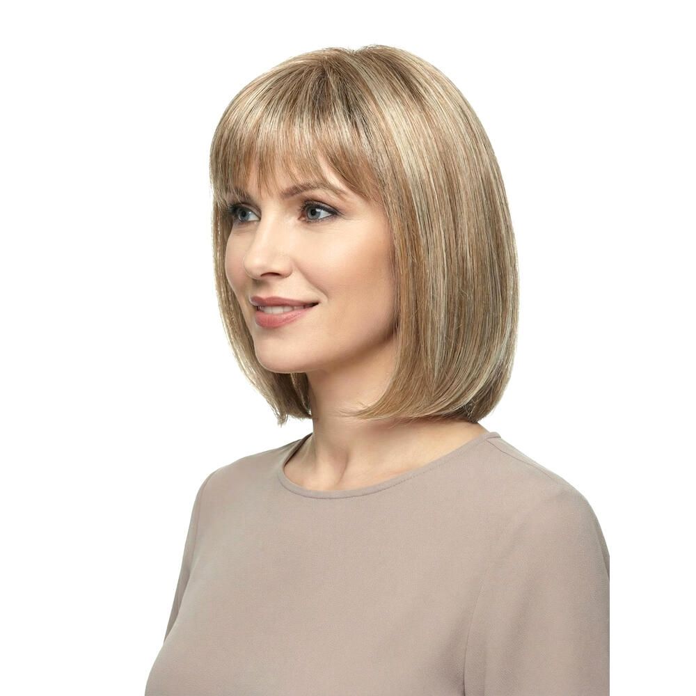 Perücke mit kurzem, blondem Haar und Pony. Die Frau trägt ein beiges Oberteil. Seitenansicht.