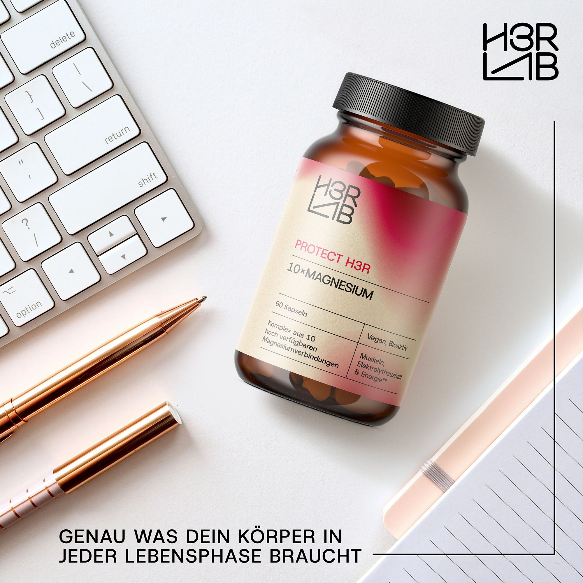 Braune Glasflasche mit Etikett. Produktname und Logo. Auf Schreibtisch mit Tastatur, Stiften und Notizbuch.
