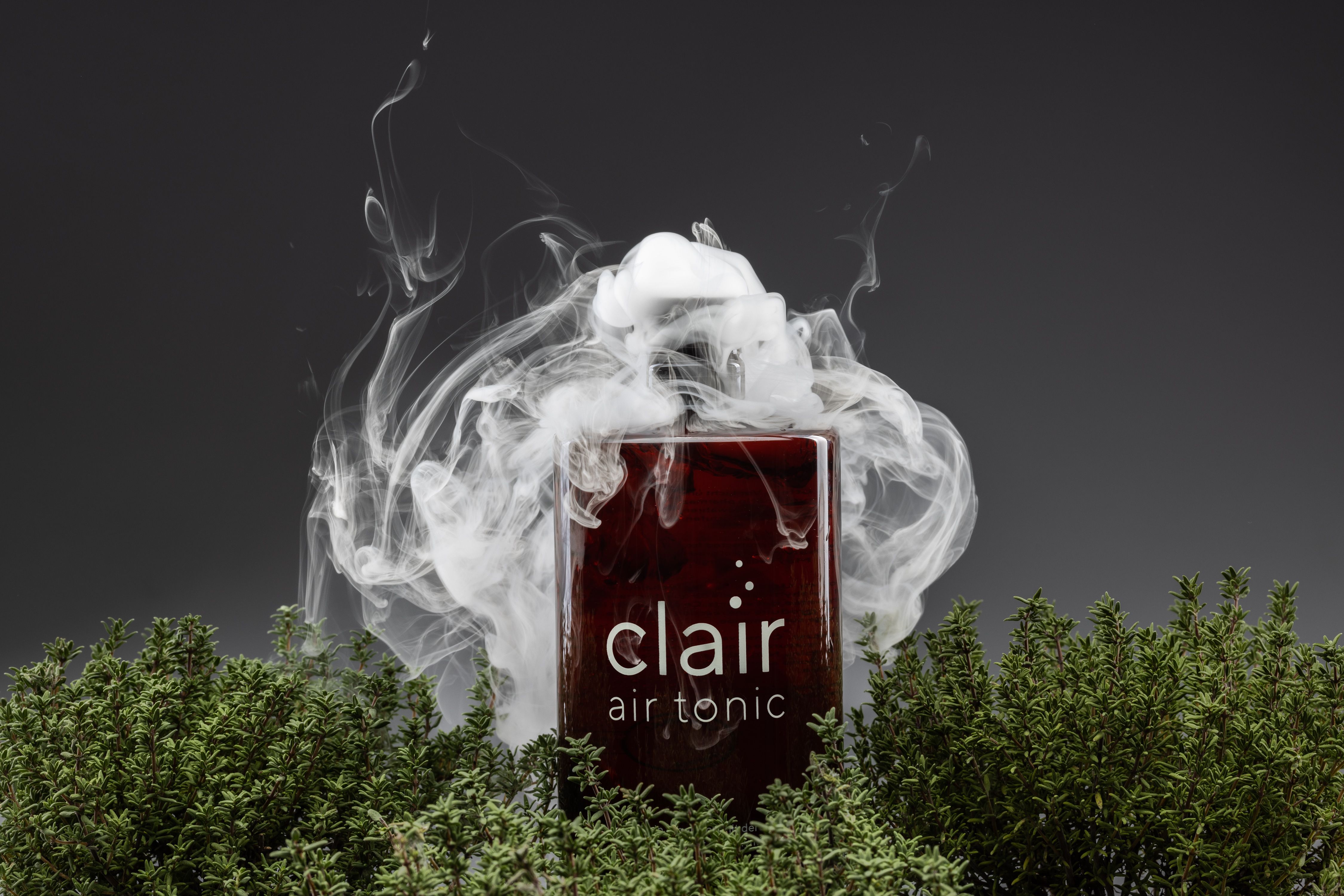 Eine Flasche mit schwarzem Deckel und rotem Inhalt. Aufschrift: clair air tonic. Rauch umgibt die Flasche.