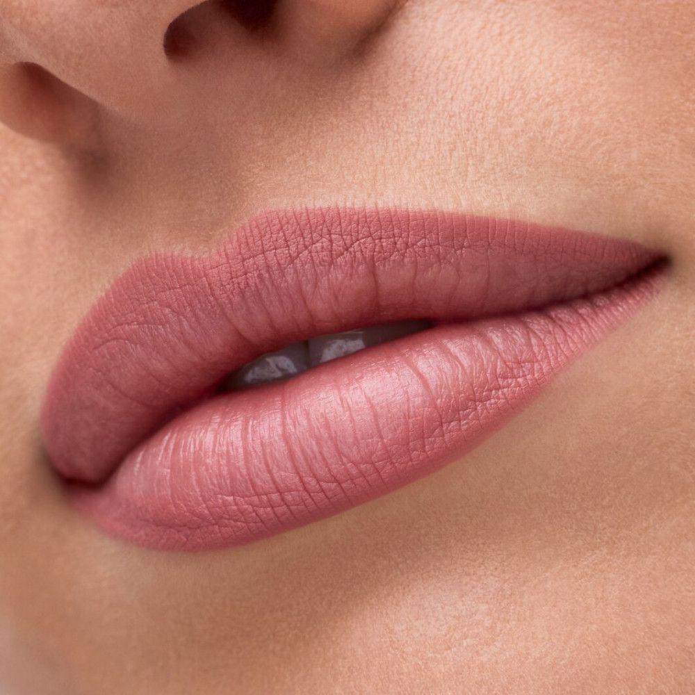 Nahaufnahme von Lippen, geschminkt mit rosa Lippenstift. Glatte Textur, gleichmäßige Farbe.