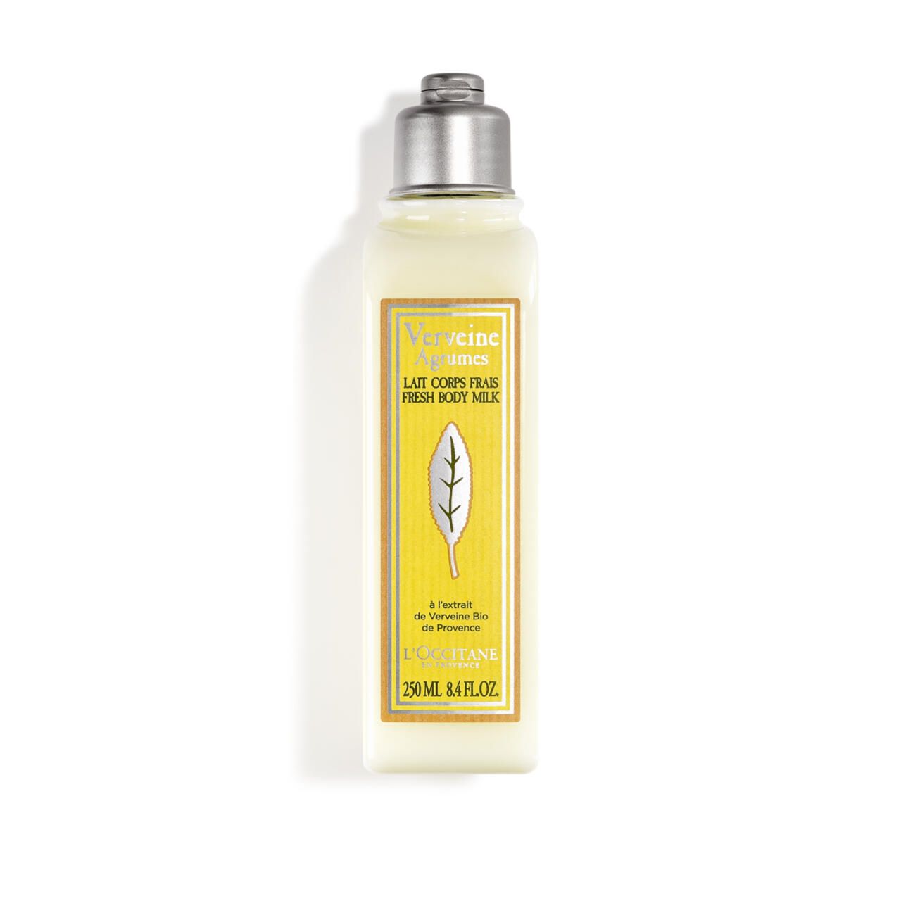 Körpermilch-Flasche mit silbernem Deckel. Gelbes Etikett mit Text und Blatt-Illustration. L'Occitane Sommer-Verbene.