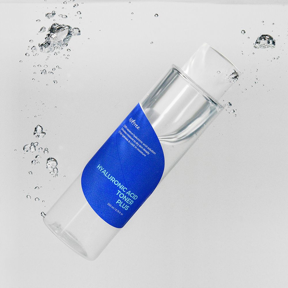 Transparente Flasche mit blauem Etikett im Wasser. Aufschrift: Hyaluronic Acid Toner Plus. Blasen.