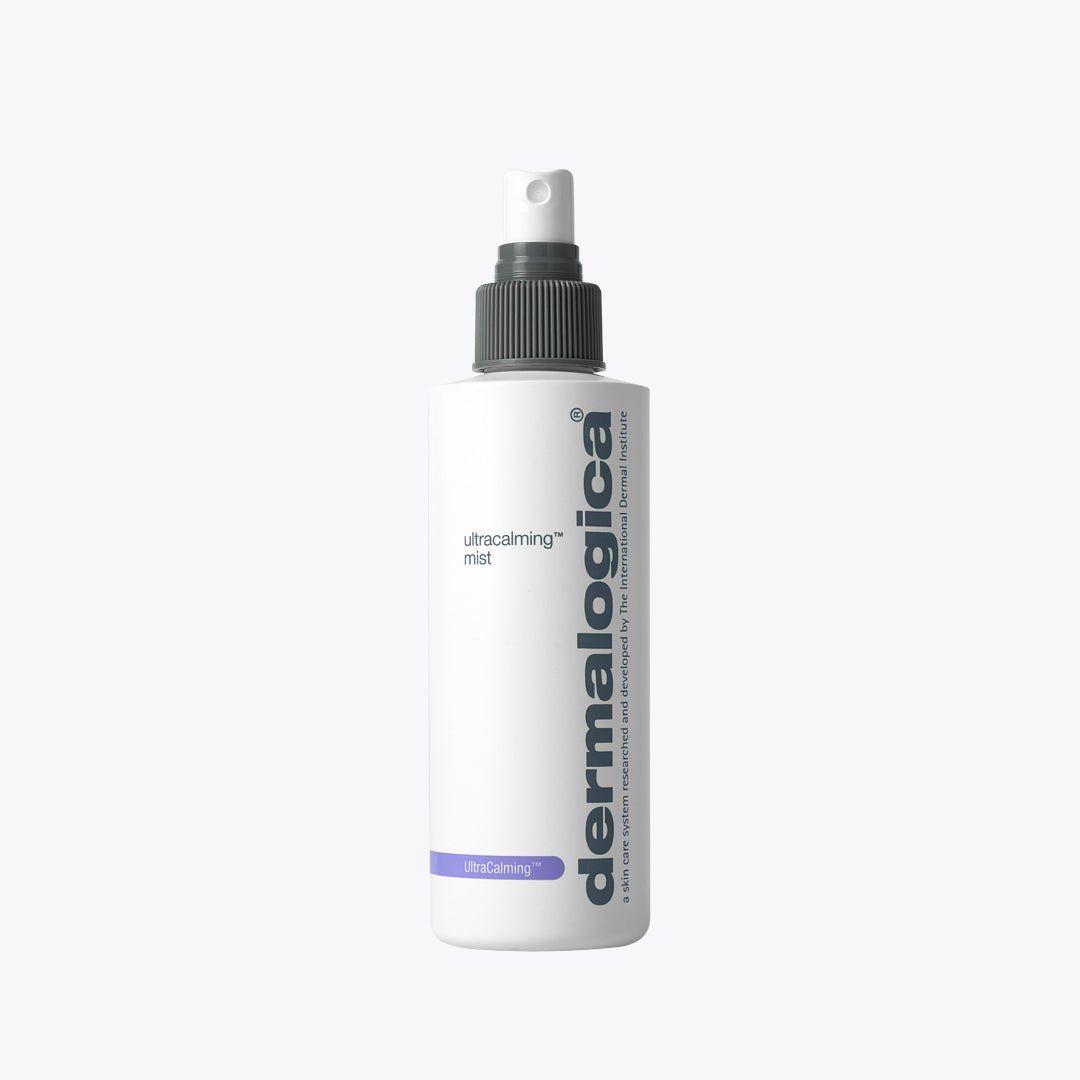 Flacone bianco di Dermalogica UltraCalming Mist con erogatore grigio. Il nome 'Dermalogica' è stampato verticalmente sul flacone. Sotto, 'UltraCalming mist' è scritto in caratteri più piccoli. Una striscia viola e la scritta 'UltraCalming' sono visibili nella parte inferiore del flacone.
