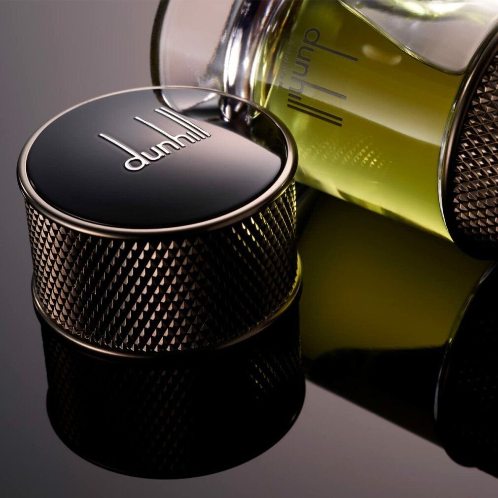 Schwarzer Deckel mit dunhill-Logo. Der Deckel liegt neben einem Flakon mit gelber Flüssigkeit. Reflektion auf schwarzem Hintergrund.