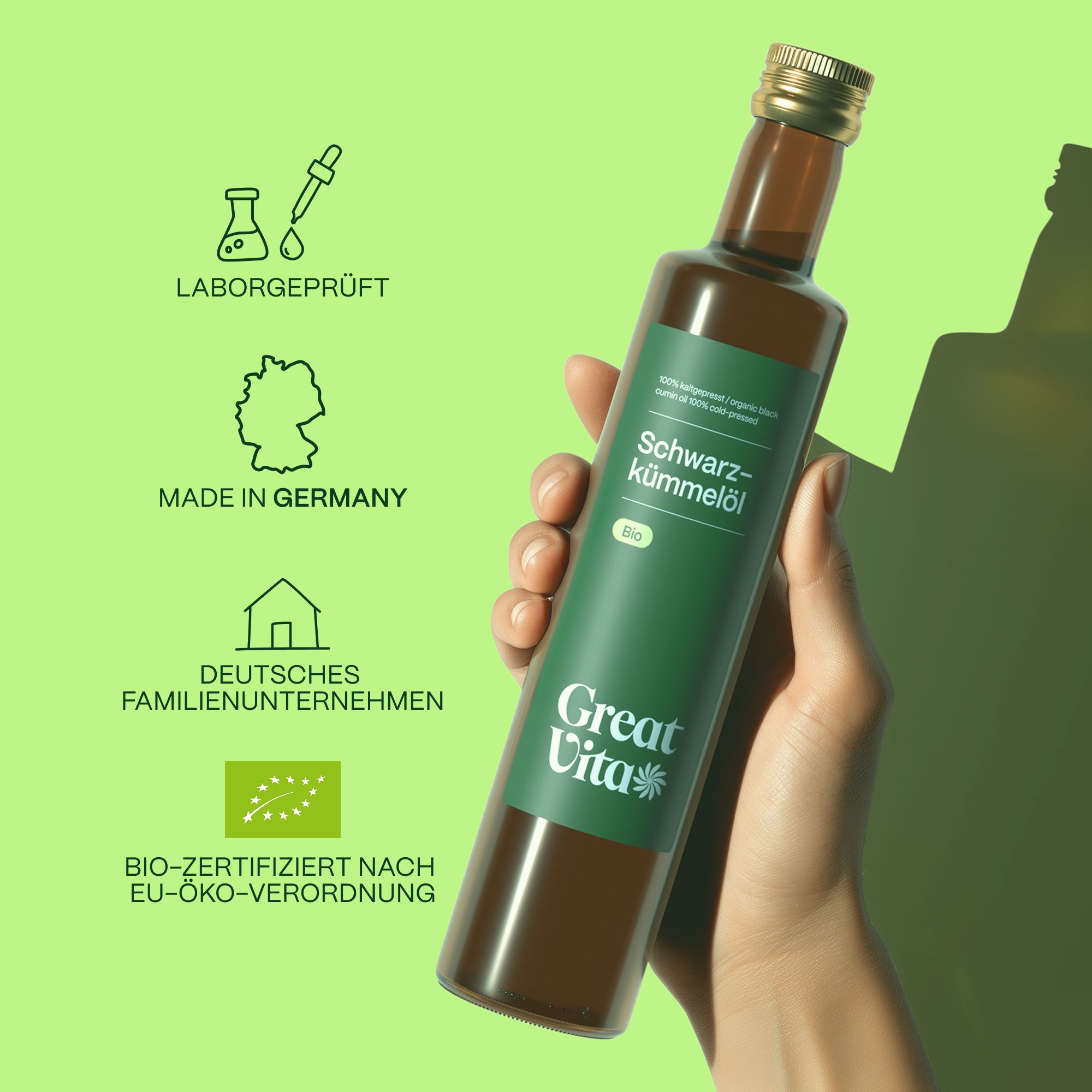 Hand hält eine Flasche GreatVita Bio Schwarzkümmelöl. Grüne Etikett mit Produktinformationen. Logo und Zertifizierungen.