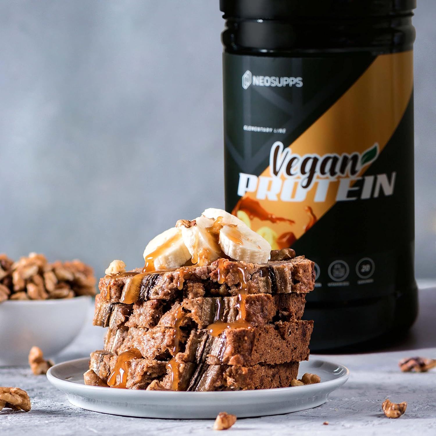 Ein Stapel Bananenbrot mit Walnüssen und Vegan Protein Dose. Auf der Dose steht "Vegan Protein" und "Neosupps".