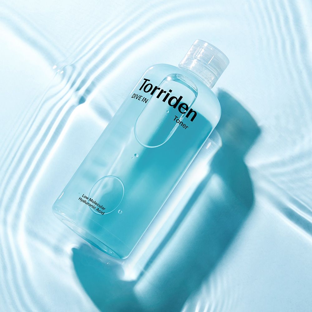 Torriden DIVE IN Toner mit Hyaluronsäure in einer durchsichtigen Flasche, umgeben von Wasserwellen.