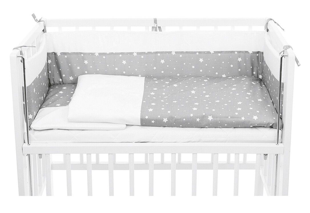 Bett-Set mit Sternenmuster in einem Babybett. Graue Bettwäsche mit weißen Sternen, weißes Kissen und Nestchen.