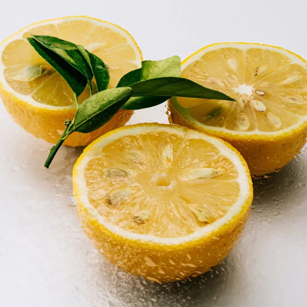 Zitronen, halbiert, mit Blättern. Gelbe Fruchtfleisch, grüne Blätter. Nahaufnahme, helle Oberfläche.