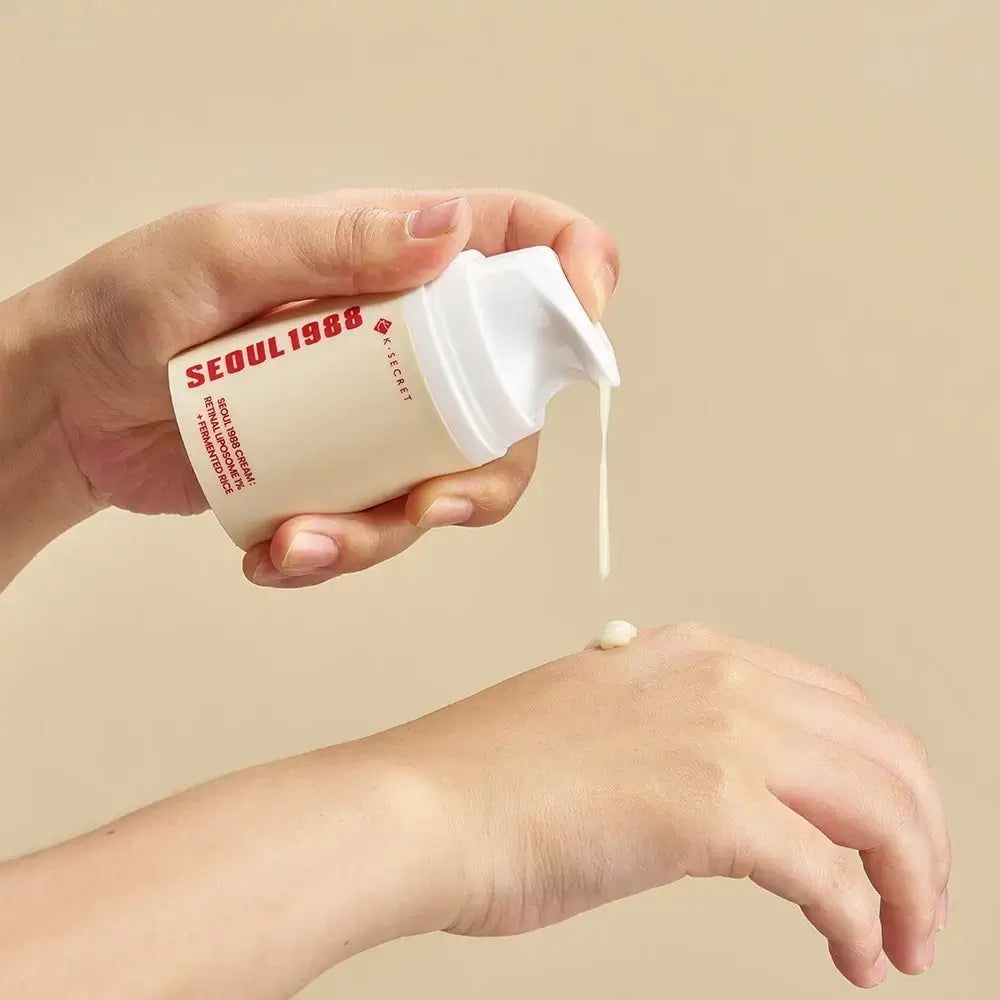 Beige Flasche mit weißem Pumpspender, aus dem eine weiße Creme auf eine Handfläche getropft wird. Text auf der Flasche: SEOUL1988.
