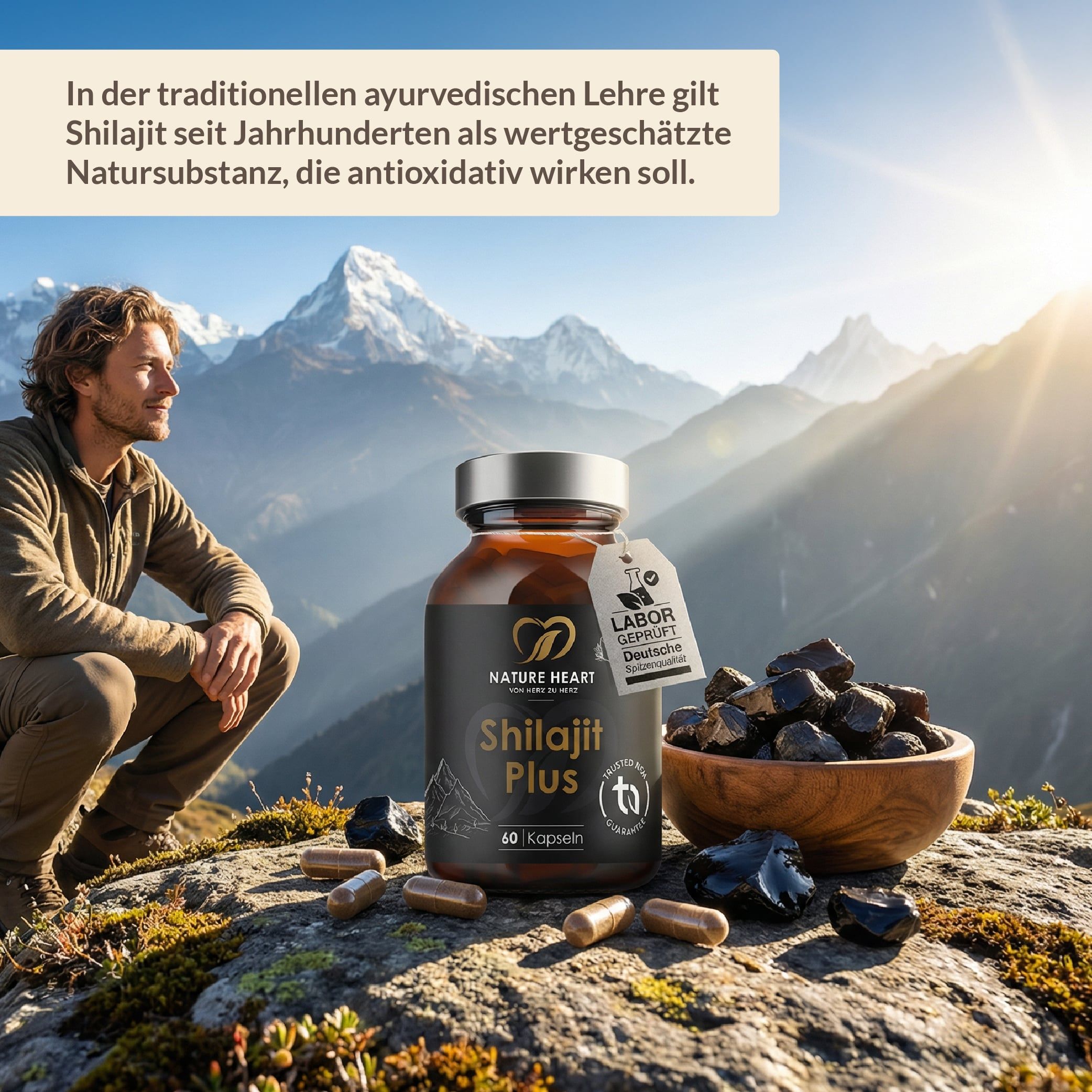 Mann sitzt vor Berglandschaft. Neben ihm: Flasche Shilajit Plus, Schale mit Shilajit-Harz, Kapseln. Labor-Siegel.
