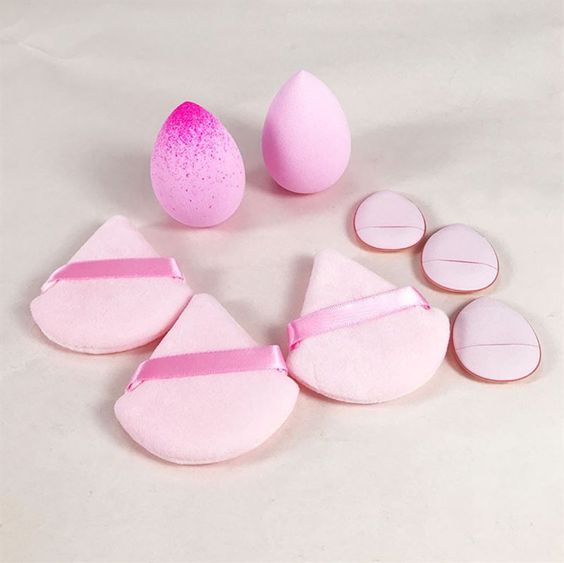 Make-up-Schwämme in verschiedenen Formen und Farben. Tropfenförmige und dreieckige Schwämme mit Bändern. Mehrere Schwämme sind sichtbar.