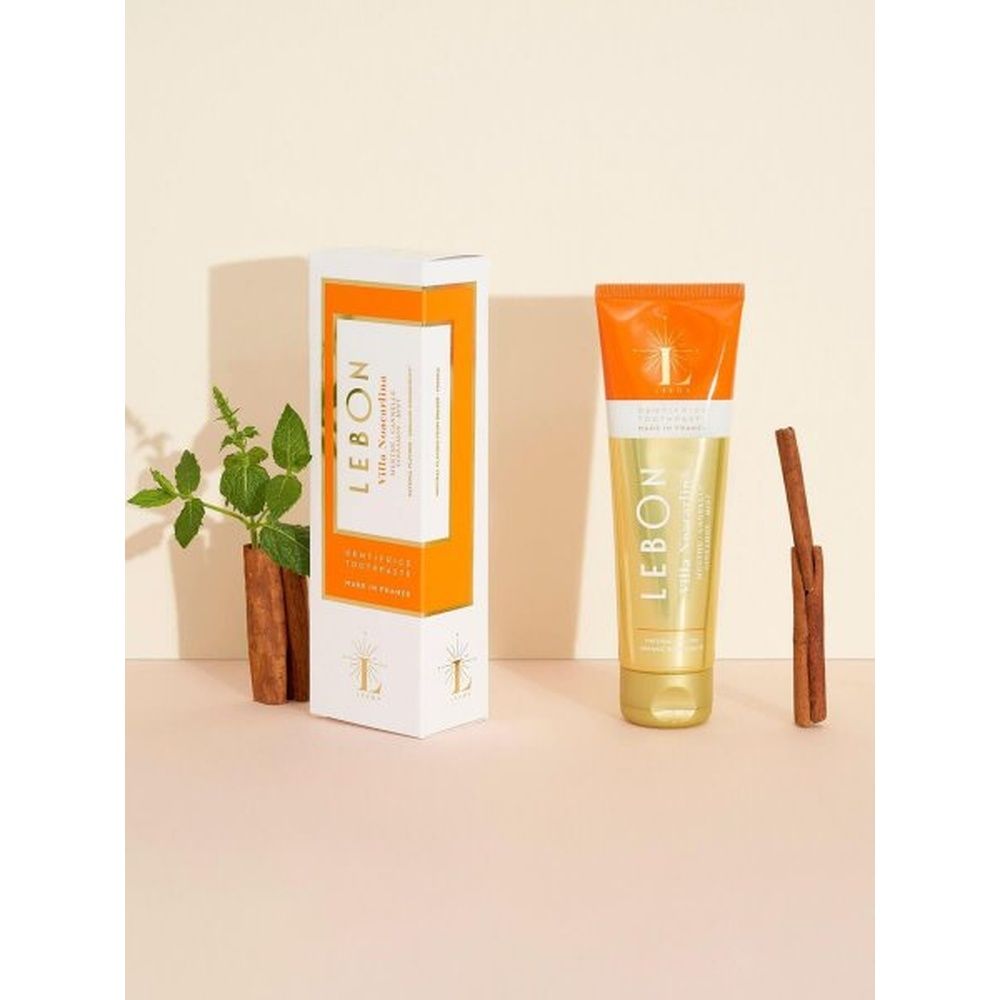 Zahnpasta-Tube LEBON Villa Noacarlina und Verpackung. Orange-weiße Schachtel und Tube. Zimtstange und Pflanze daneben.