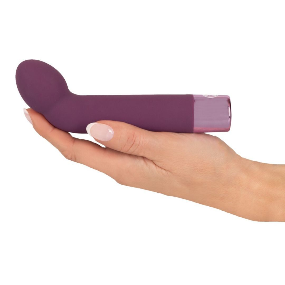 Lila Vibrator in einer Hand gehalten. Die gebogene Spitze zeigt nach links.