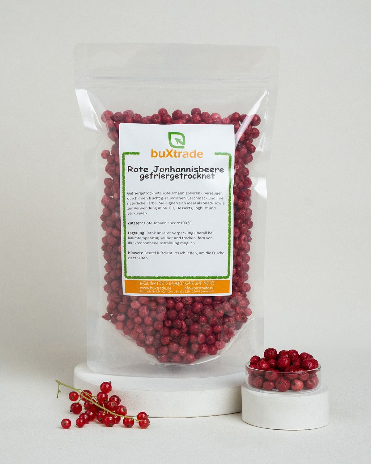 Gefriergetrocknete rote Johannisbeeren in Beutel und Schale, mit frischen Beeren.