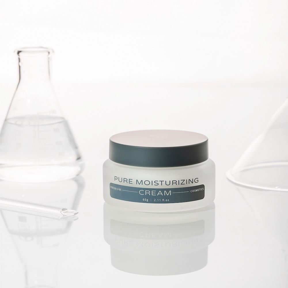 Creme-Glas mit Deckel. Aufschrift: Pure Moisturizing Cream. Im Hintergrund Laborutensilien.