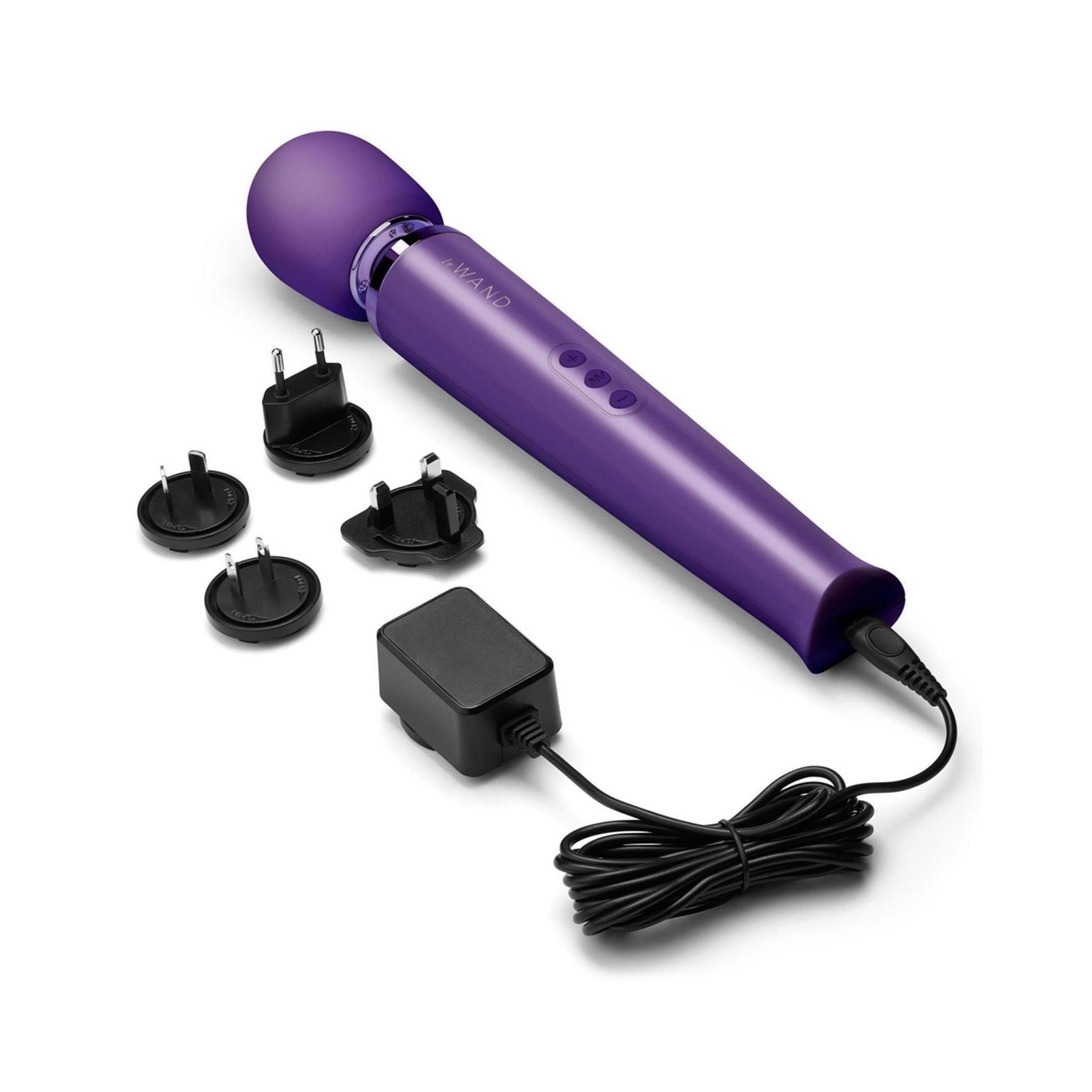 Lila Stab mit abgerundetem Kopf, drei Knöpfen, Netzteil und verschiedenen Adaptern.
