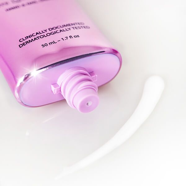 Close-up van een roze handcrèmetube. Crème wordt eruit geperst. Tekst: 50 ml - 1.7 fl oz.
