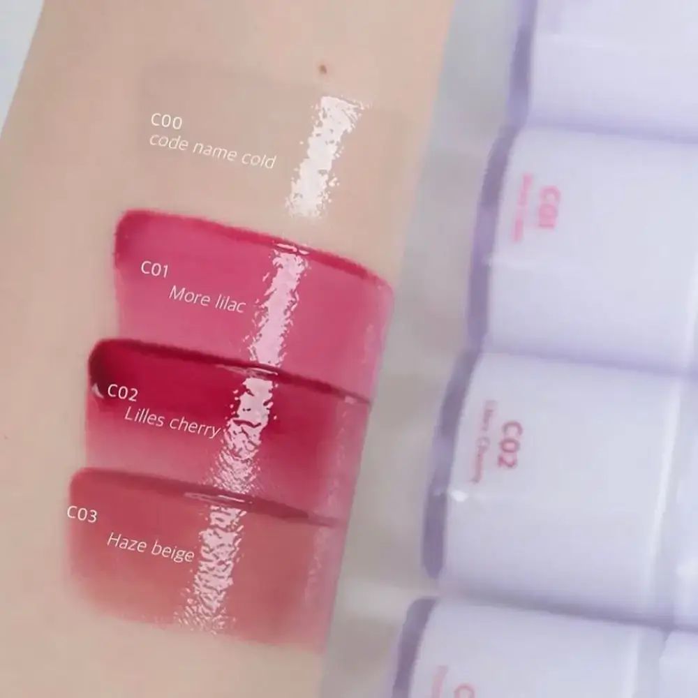 Produktmuster auf Haut. Text: C00, C01, C02, C03. Mehrere Lipgloss-Tuben.
