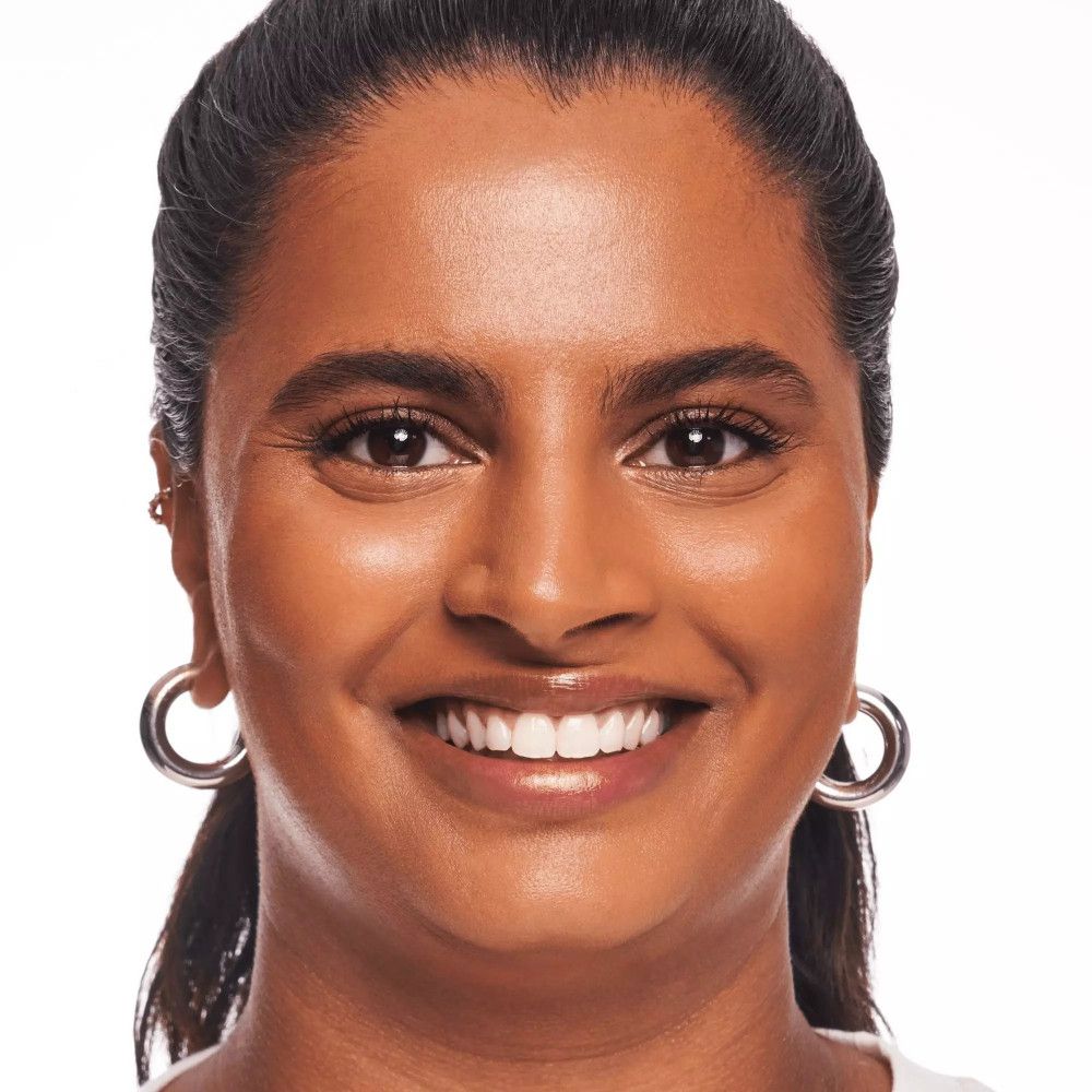 Porträt einer Frau mit getöntem Serum. Hautton: mittel. Sie lächelt. Große silberne Ohrringe.