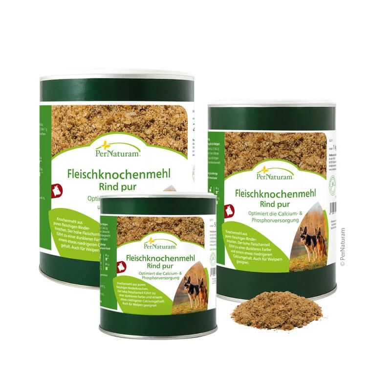 Drei Dosen Fleischknochenmehl Rind pur. Grün-weiße Etiketten mit Produktname und Logo. Geöffnet, Inhalt sichtbar. Haufen daneben.