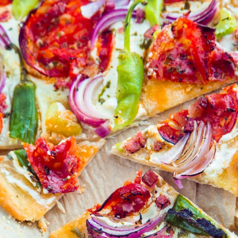 Pizza-Scheiben mit Tomaten, Zwiebeln und Paprika. Nahaufnahme, Ansicht von oben.