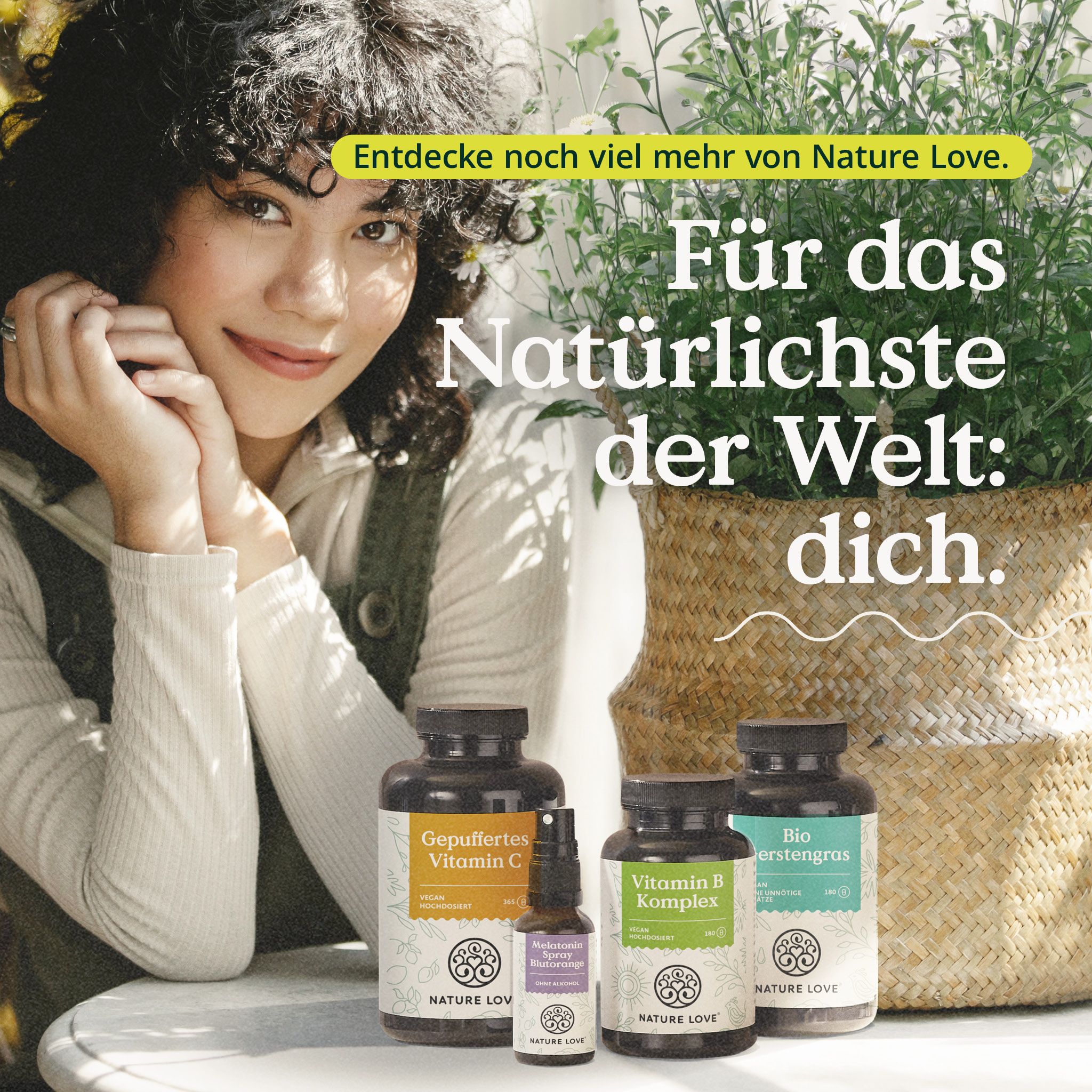 Frau mit Produkten von NATURE LOVE®. Gezeigt werden Flaschen mit Vitamin C, Vitamin B Komplex und Bio Erstengras.