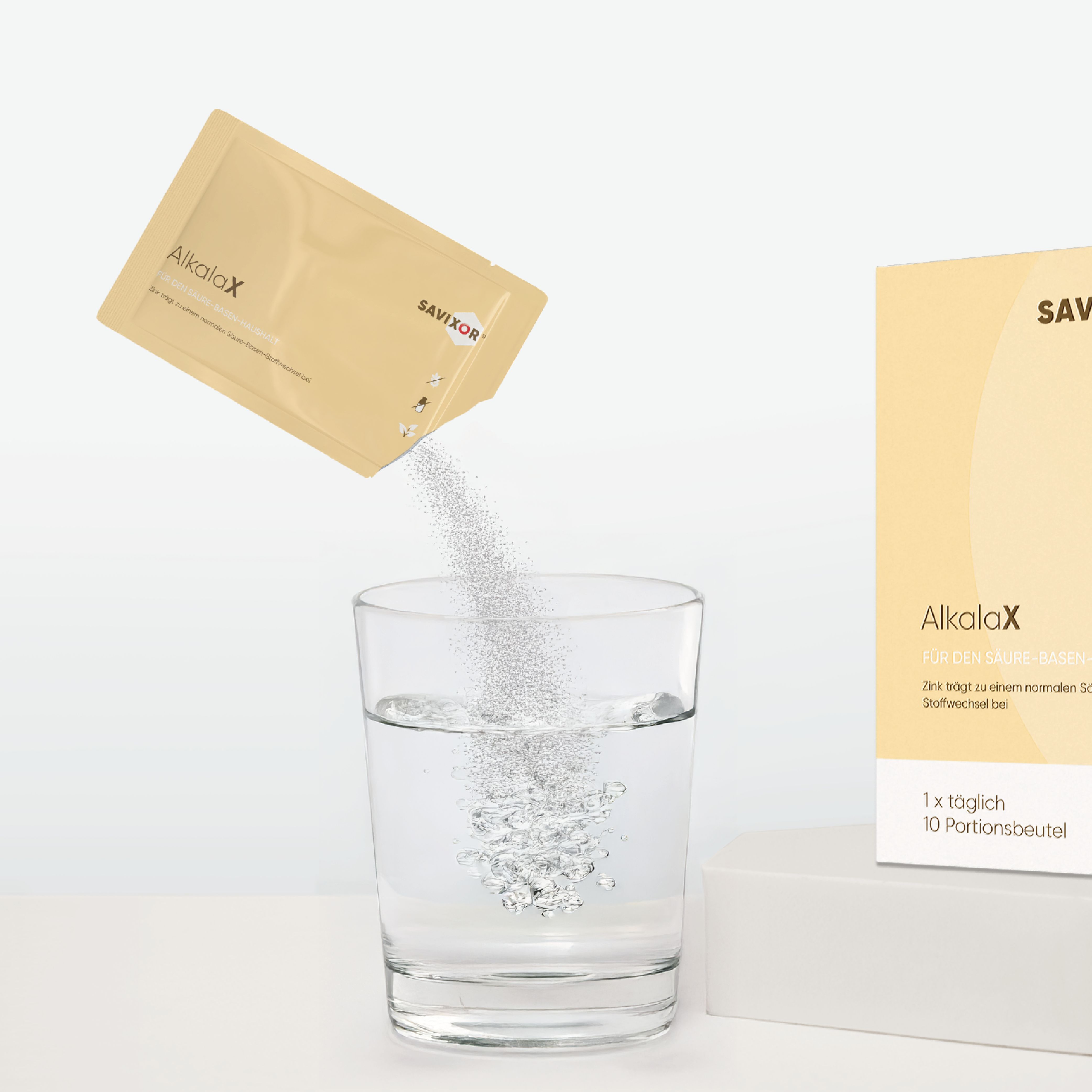 Glas mit Wasser, in das Pulver aus einem Sachet gegossen wird. Daneben eine Packung und ein Sachet.