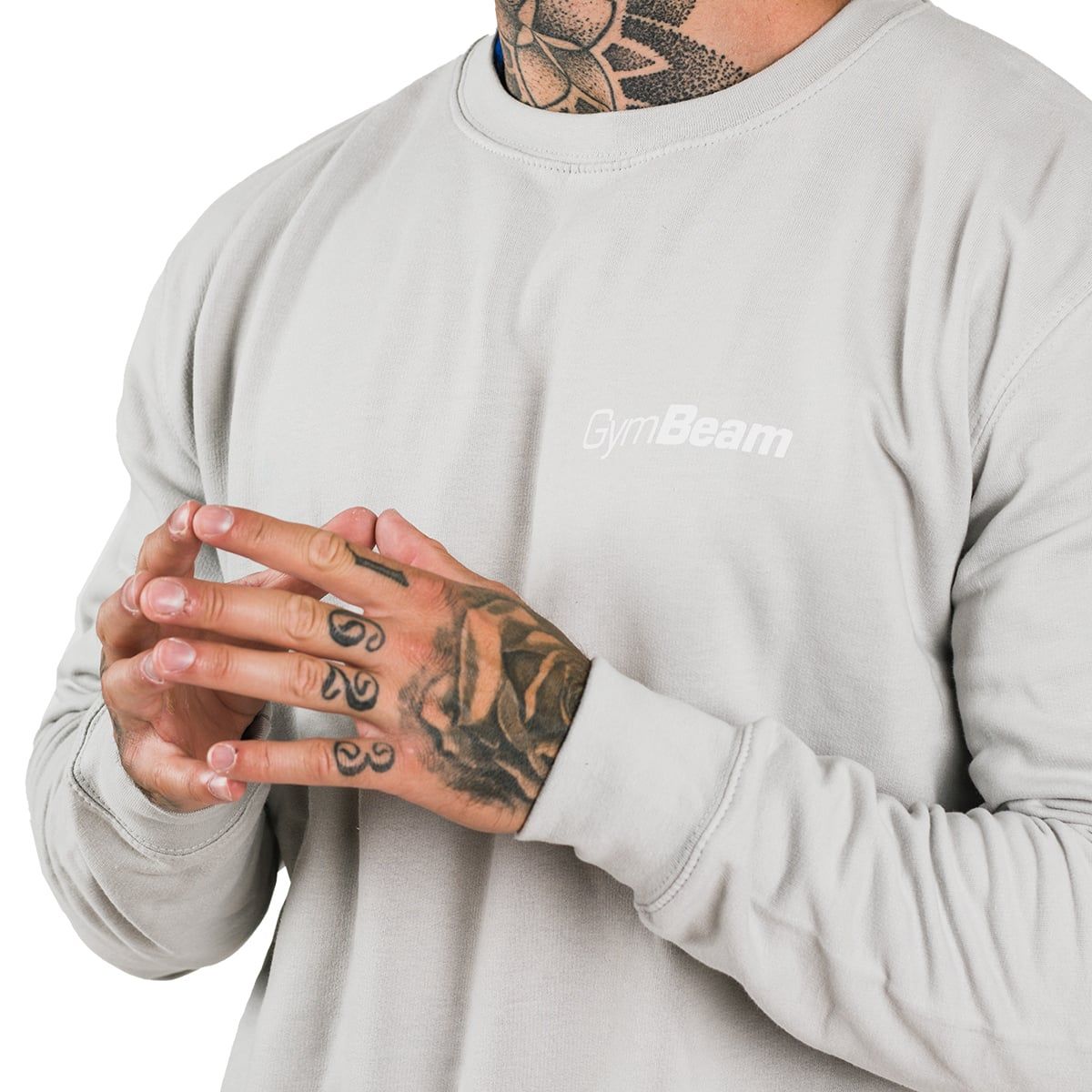 Nahaufnahme der Hände eines Mannes mit Tattoos, der einen grauen Pullover trägt.