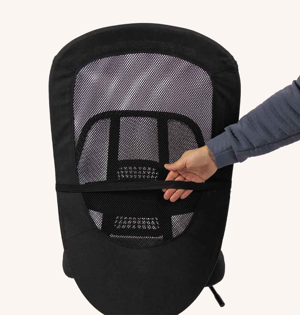 Rückenstütze mit schwarzem Netzgewebe. Hand greift nach einem Befestigungsband. Weißer Hintergrund.