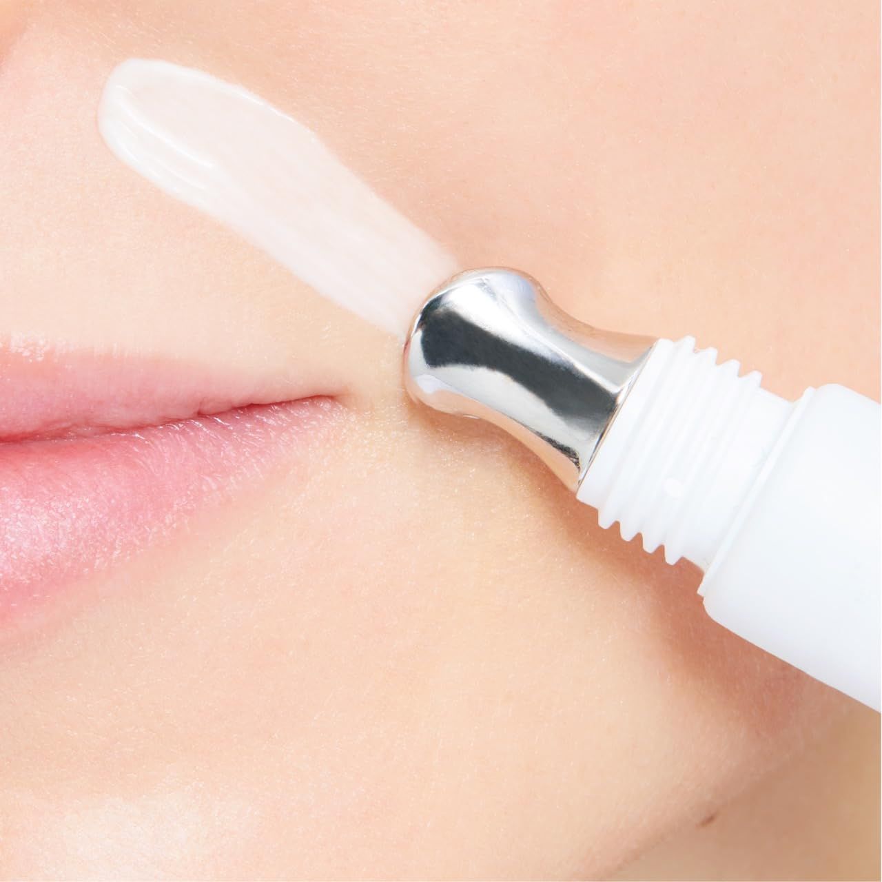 Nahaufnahme des Gesichts. Applikator des Cellfiller-XT auf Lippen. Creme wird aufgetragen. Weißer Hintergrund.