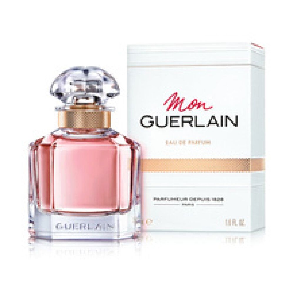 Parfümflasche mit Verpackung. Flakon mit rosa Flüssigkeit, goldfarbenem Hals und transparentem Deckel. Verpackung mit Schriftzug Mon Guerlain.