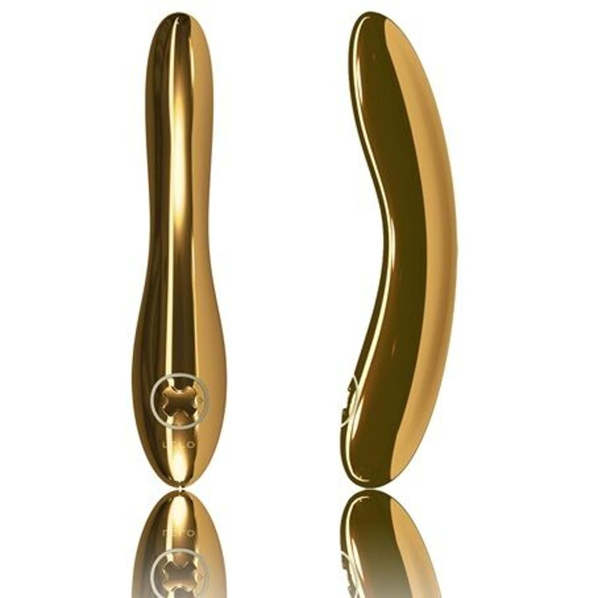 Zwei goldfarbene Vibratoren. Einer ist von vorne, der andere von der Seite abgebildet. Beide sind auf einer spiegelnden Oberfläche platziert.